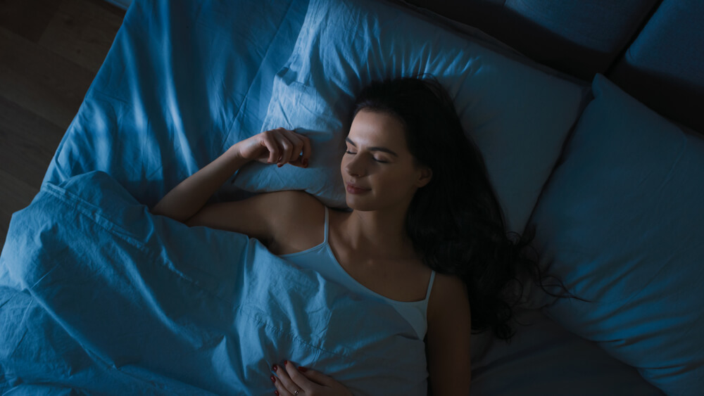 Top view of a woman resting on her bed at nighttime.