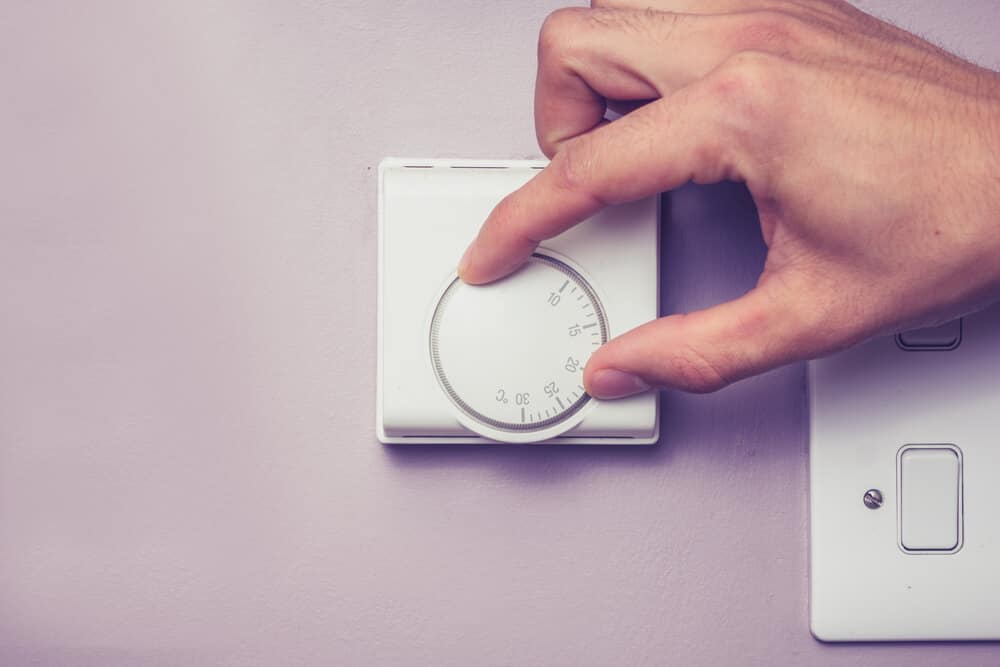 Hand turning dial on thermostat, best temperature for sleep concept.