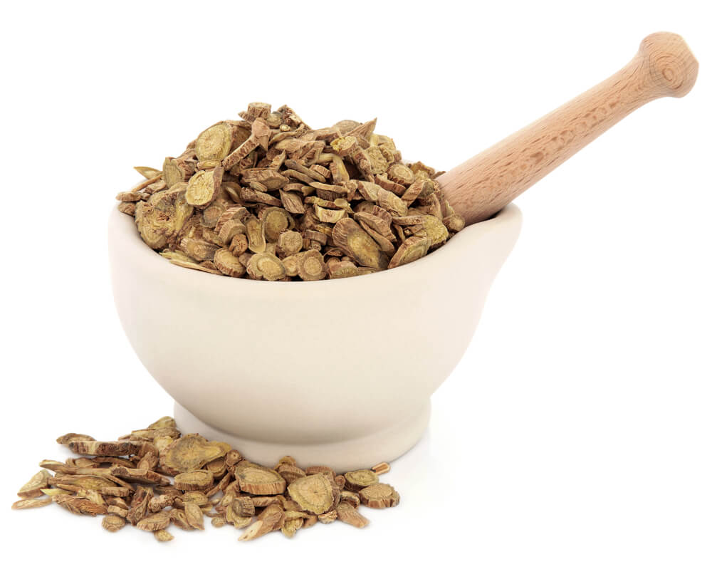 Skullcap root chinese herbal medicine in a stone mortar with pestle over white background. Huang qin. Scutellaria.