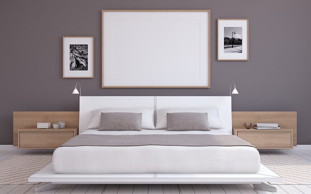 A white bed frame against a dark gray wall.